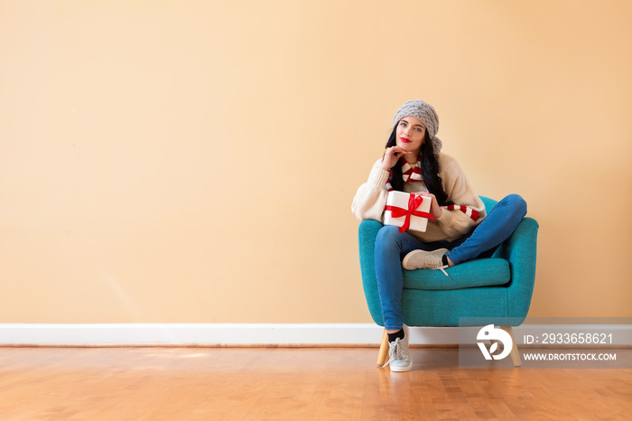 Young woman holding a gift box sitting in a chair