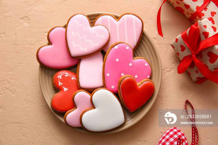 Plate with tasty heart shaped cookies and gift boxes on beige background