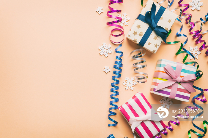 Holiday flat lay with gift boxes wrapped in colorful paper and tied decorated with confetti on color