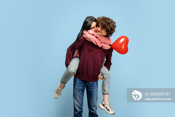 Heart balloon, embracing. Beautiful couple in love on blue studio background. Saint Valentines Day,