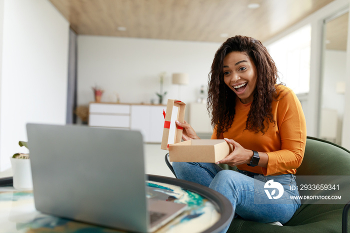 Happy Woman Opening Gift Box In Front Of Laptop