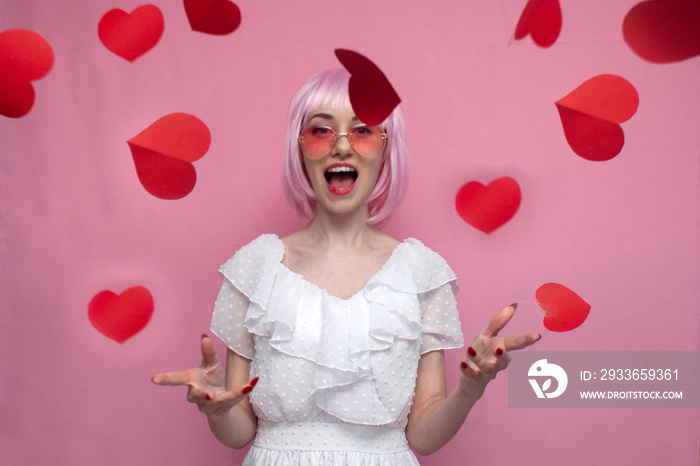 crazy girl with pink hair in a dress screams and throws confetti on a pink background, a woman with 