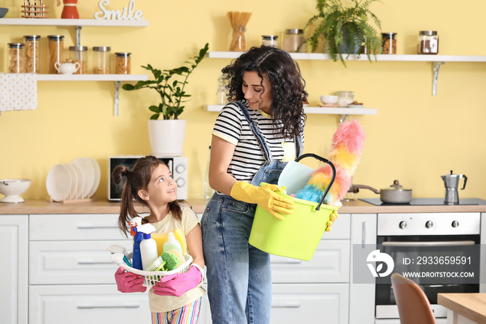 Mother and daughter with cleaning supplies in kitchen