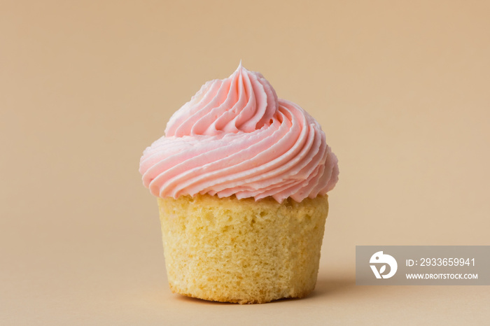 Close-up of vanilla cupcake with pink whipped butter cream top. Cream cheese frosting on muffin deco