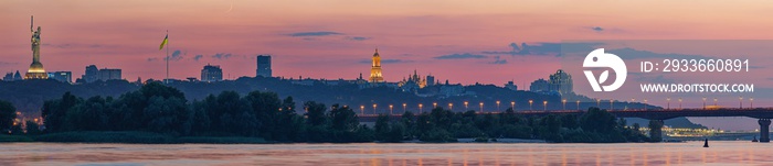 View of the Kiev-Pechersk Lavra, Kiev bridges and the Dnieper River, after sunset, a thin crescent moon is seen in the pink sky.