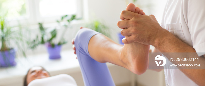 Young woman exercising during physiotherapy with help of physiotherapist in the hospital