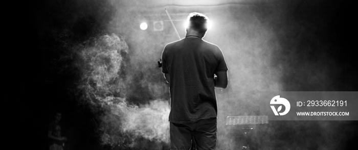 View from the back of a man playing the violin on stage