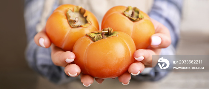 Woman holding ripe persimmons, closeup