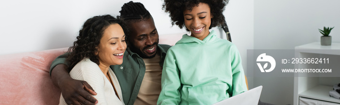 happy african american family watching comedy movie on laptop in living room, banner.