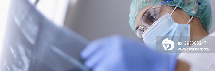 Doctor in protective medical mask looks at an X-ray. A wide variety of medical services with the use of modern developments and achievements concept