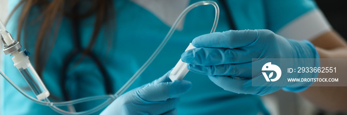 Close-up of female hands in sterile gloves putting dropper to sick patient. First aid procedures. Giving medical care. Healthcare and prevention concept