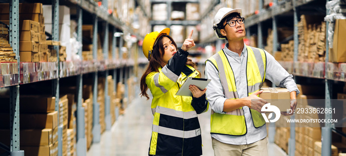 Asian two engineer in helmet team order detail on tablet computer for checking goods and supplies on shelves with goods background in warehouse.logistic and business export