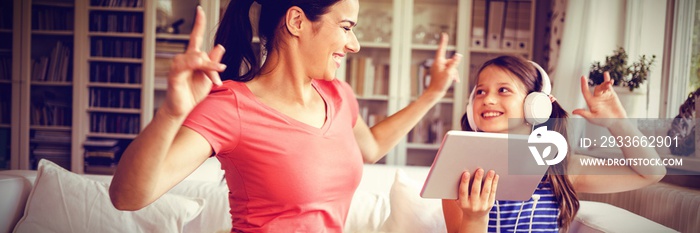 Happy mother and daughter using digital tablet and dancing