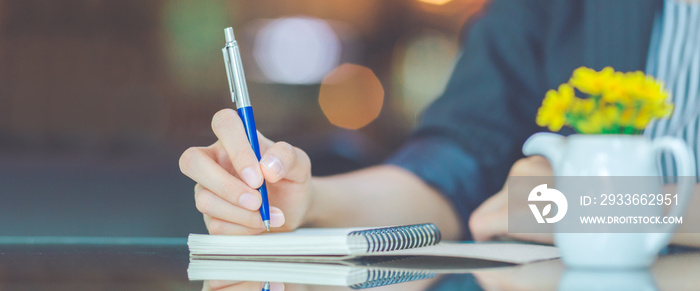 Business woman writing on a notebook.with a pen in the office.Web banner.