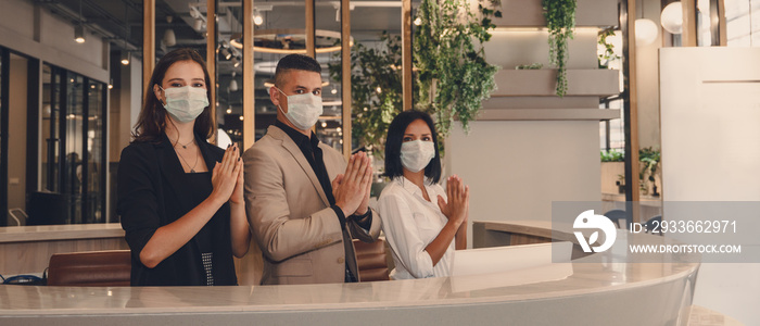 hotel receptionist wearing medical mask and show greeting with thai wai for being new greeting practice during coronavirus covid 19 pandemic, new greeting practise in coronavirus covid 19 pandemic