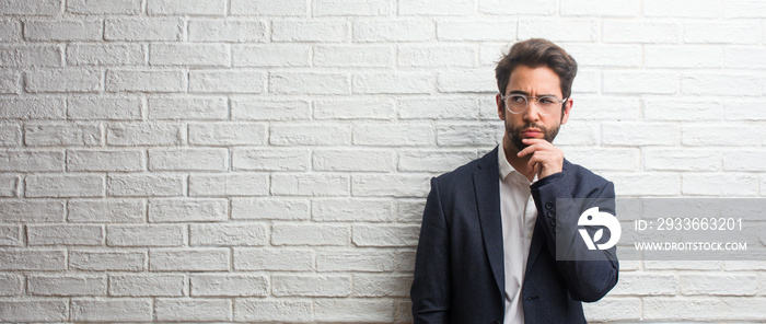 Young friendly business man doubting and confused, thinking of an idea or worried about something