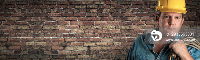 Male Contractor In Hard Hat Holding Cable In Front Of Old Brick Wall Banner with Copy Space