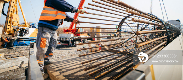 Unloading iron piles from the truck before starting of the construction of a concrete bridge in the field