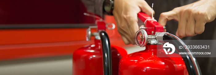 Fire protection engineer check the safety pin of red fire extinguishers tank in the building concepts for fire prevention emergency and safety of fire services and training.