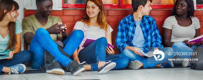 Group of multi ethnic teenagers seated in the hallway, talking each other