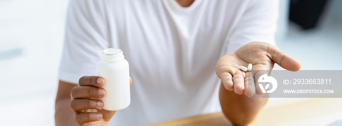 Male hands holding capsules and an open bottle close-up. Painkiller, headache medication or vitamins concept