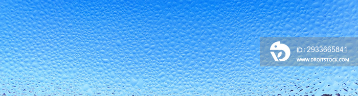 raindrops on a wet window against a clear blue sky