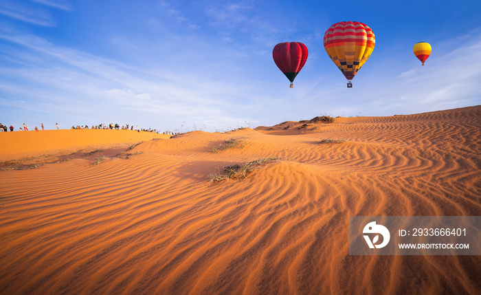 Hot air balloons flying over beautiful sand dunes sunset in the Mui Ne Red Sand Dunes in the North of Mui Ne Village, about 25 km from Phan Thiet City, Vietnam