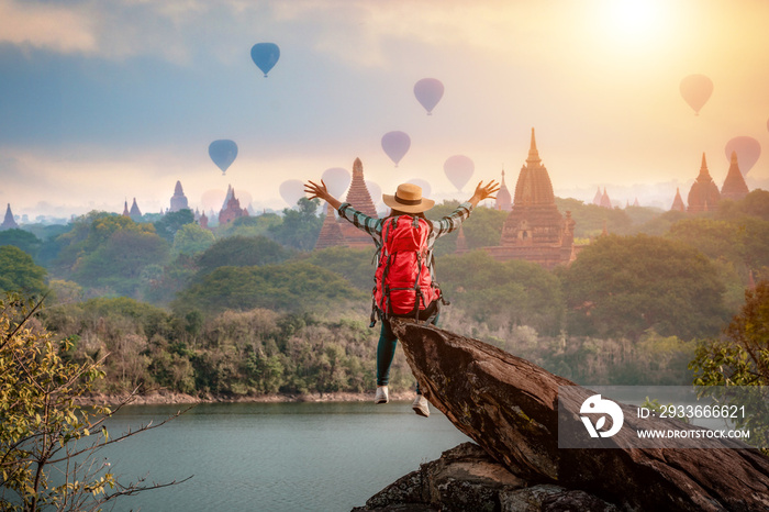 Woman traveler sitting on stone freedom hands up watching and enjoying with Bagan pagoda landscape  in Mandalay Myanmar.