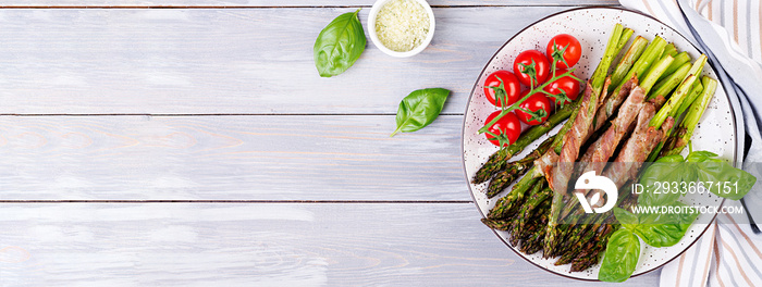 Grilled green asparagus wrapped with bacon on wooden table. Banner. Top view