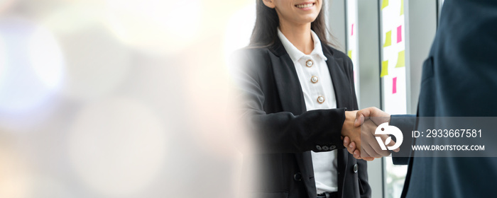 Business people handshake in corporate office in widen view showing professional agreement on a financial deal contract.