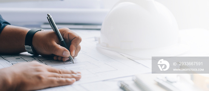 architect drawing on a blueprint on architectural project at the construction site at office desk in the office.Architectural and engineering concept.