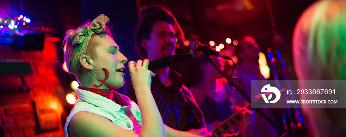 Rock band playing on the concert stage in the small night club