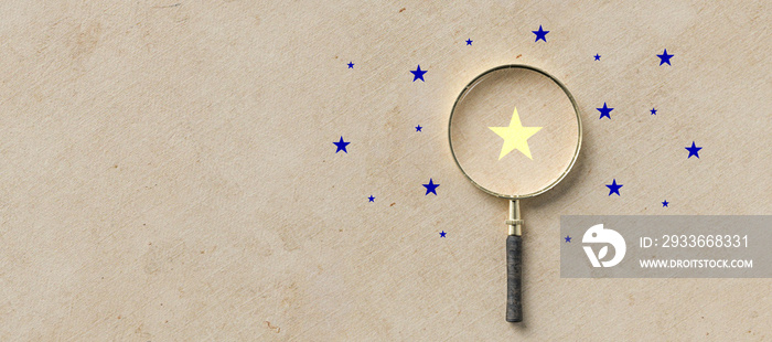 magnifying glass with a yellow star mark as symbol for finding a solution on paper background