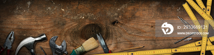 Group of hand tools on a wooden work table with copy space and dark shadows. Home improvement and do it yourself concept