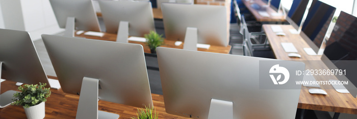 Many silver monitors stand on a wooden table in office closeup. Programmer professional education concept