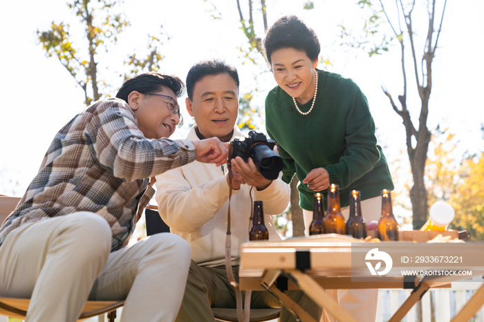 一群中老年人坐在露营地看数码相机