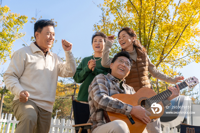 一群中老年人在房车露营地弹吉他唱歌