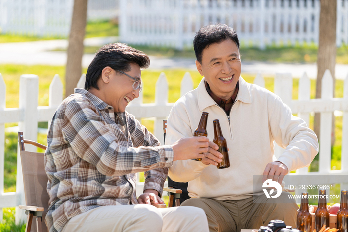 两个老年男人坐在露营地喝啤酒