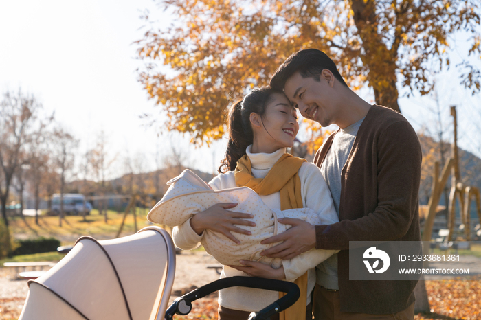 年轻夫妻推着婴儿车散步