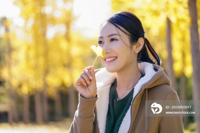 快乐的年轻女子手拿银杏叶