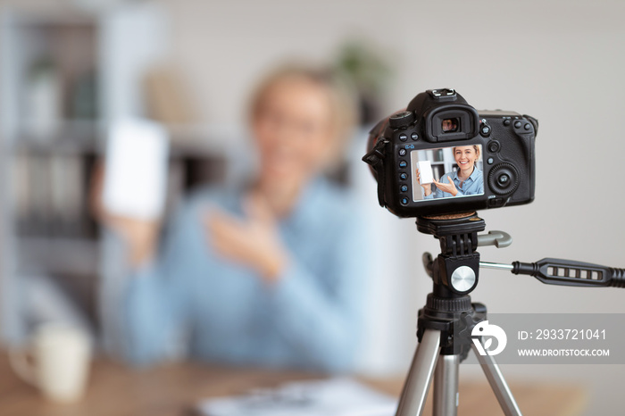 女性视频记录者对新设备进行视频评论，在屏幕上录制相机的选择性焦点，