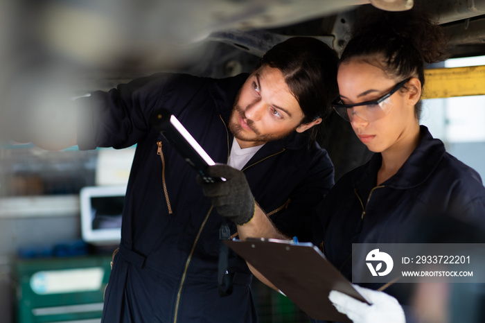 Hispanic Female trainee Mechanics Working Underneath Car Together Car maintenance and auto service g