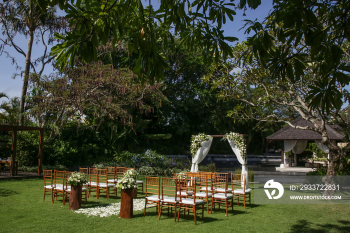 热带花园里美丽浪漫的户外婚礼，木制椅子和简单的凉亭装饰