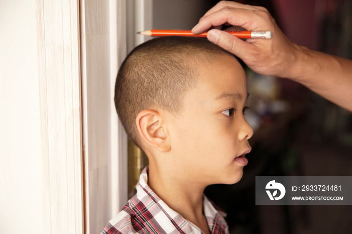 Father measuring son in doorway