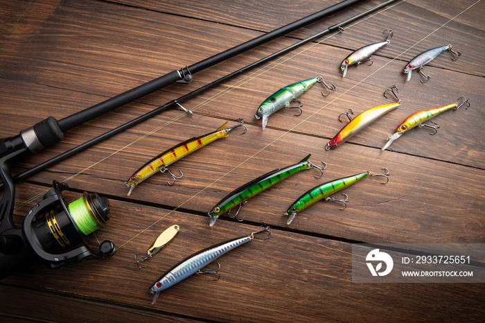 Fishing tackle - fishing spinning rod, hooks and lures on wooden background. Active hobby recreation