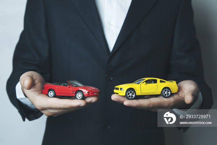 Man holding two small cars