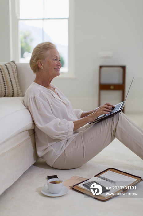 Senior woman using laptop on living room floor