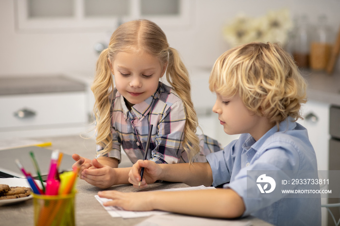 Two kids sitting at the table and drawing