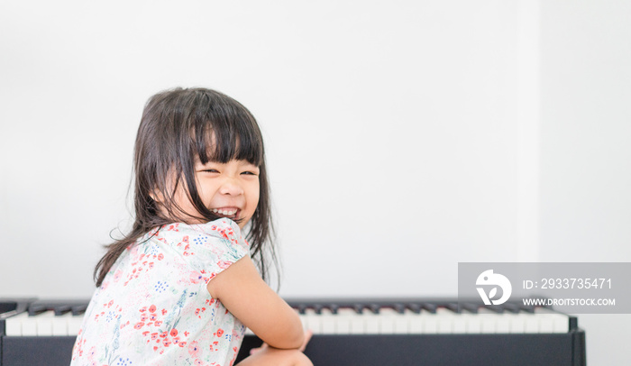 漂亮的亚洲小女孩在客厅或音乐学校弹钢琴。幼儿园的孩子有f