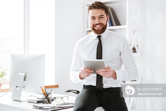 Businessman sitting in office while holding tablet .